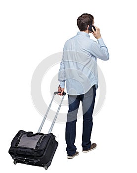 Back view of walking business man with suitcase talking on the phone
