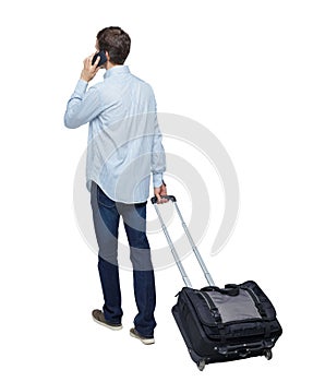 Back view of walking business man with suitcase talking on the phone