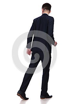 Back view of walking businessman looking behind