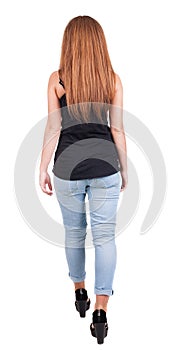 Back view of walking woman. beautiful redhead girl in motion.