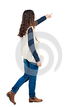 Back view of walking woman. beautiful redhead girl pointing.