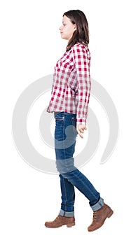 Back view of walking woman in checkered shirt.