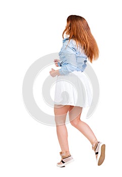 Back view of walking woman in dress. beautiful redhead girl in
