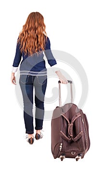 Back view of walking woman with suitcase.