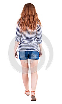 Back view of walking young beautiful redhead woman