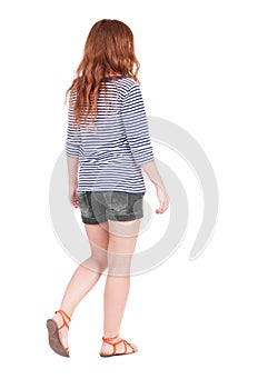 Back view of walking young beautiful redhead woman