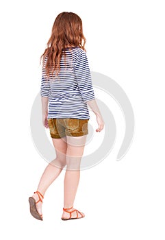 Back view of walking young beautiful redhead woman