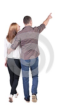 Back view of walking young couple (man and woman) pointing.