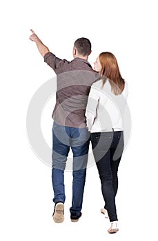 Back view of walking young couple man and woman pointing.