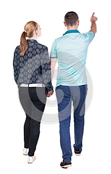 Back view of walking young couple (man and woman) pointing.