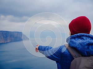 Back view of woman on shore of North sea on cold winter day.