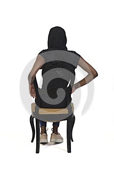 Back view of a woman with casual clothing and burka sitting on chair on