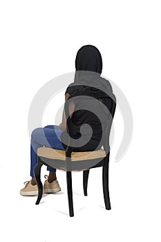 Back  view of a woman with casual clothing and burka sitting on chair