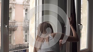 Back view of woman cleaning window with rag while doing housekeep work at home