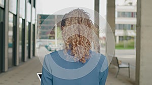 Back View of Woman With Curly Hair Walking Down the Street .