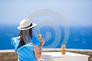 Back view of woman drinking cold coffee enjoying sea view. Beautiful woman relax during european sea vacation on the