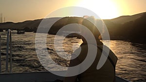 Back view of woman enjoying on boat on Nile river at sunset