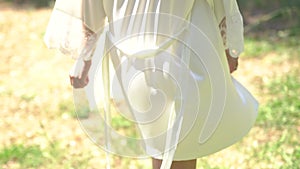 Back view of a woman in a graceful peignoir walking on a grass on a summer day