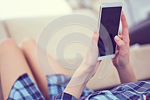 Back view of a woman hands using smart phone with blank screen close up. White phone with a black screen in the hands of