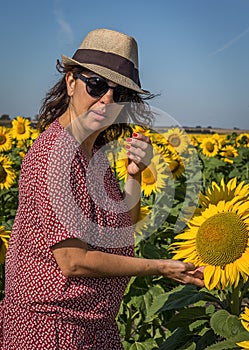 Back view of woman in hat looking at sunflower