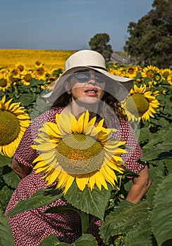 Back view of woman in hat looking at sunflower