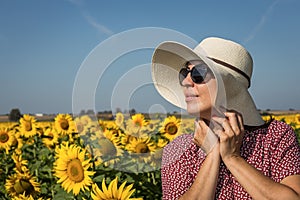 Back view of woman in hat looking at sunflower