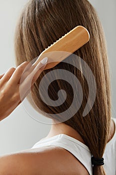 Back View Of Woman With Healthy Long Hair Brushing It With Brush