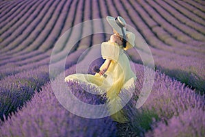 Back view woman lavender sunset. Happy woman in yellow dress holds lavender bouquet. Aromatherapy concept, lavender oil