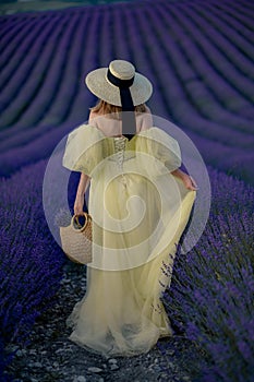 Back view woman lavender sunset. Happy woman in yellow dress holds lavender bouquet. Aromatherapy concept, lavender oil