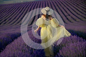 Back view woman lavender sunset. Happy woman in yellow dress holds lavender bouquet. Aromatherapy concept, lavender oil