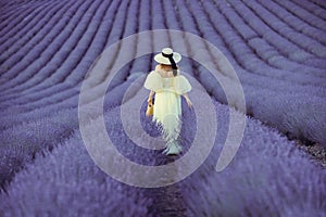 Back view woman lavender sunset. Happy woman in yellow dress holds lavender bouquet. Aromatherapy concept, lavender oil