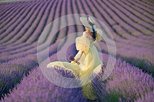 Back view woman lavender sunset. Happy woman in yellow dress holds lavender bouquet. Aromatherapy concept, lavender oil