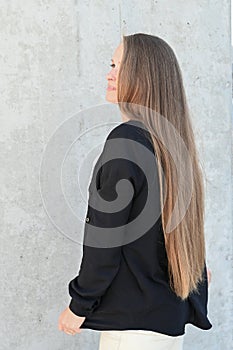 Back view of a woman with long natural blonde woman with long natural blonde hair hair outdoor. Vertical photo