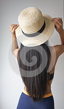 Back view of woman with long straight black hair wearing a hat