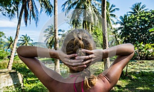 Woman looking at beautiful tropical view with palm trees and small pond