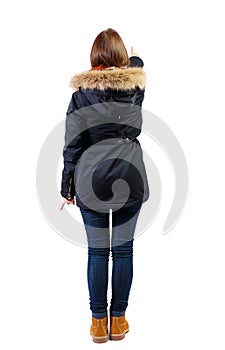 Back view of a woman in parka points his hand upwards