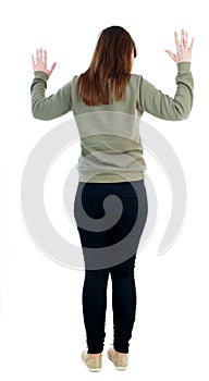 Back view of woman protects hands from what is falling from abo