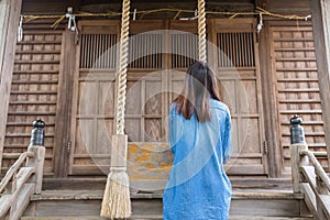 Back view of woman ringing the bell in Japanese temple