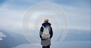 Back view of woman on shore of North sea on cold winter day.