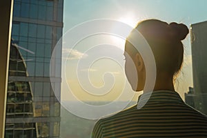 Back view of woman silhouette looking at cityscape through window of skyscraper