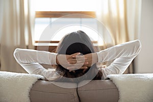 Back view of woman sit relax on sofa at home