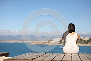 Back view of a woman sitting contemplating ocean