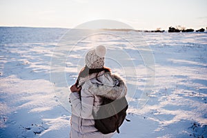 Back view of woman in snowy mountain wearing modern coat at sunset. winter season. nature