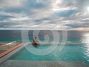 Back view of a woman standing in an infinity pool