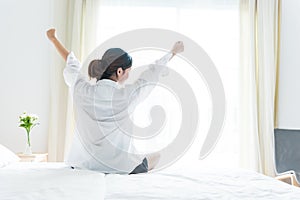 Back view of woman stretching in morning after waking up on bed