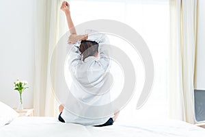 Back view of woman stretching in morning after waking up on bed