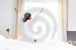 Back view of woman stretching in morning after waking up on bed