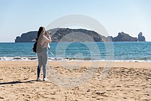 Back view of woman taking pictures with DSLR camera of islands from the beach - Medes Islands