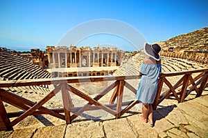 Back view of woman traveler in hat looking at amazing Amphitheater ruins in ancient Hierapolis, Pamukkale, Turkey. Grand panorama