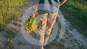 Back view, woman walking on road with bouquet of flowers, sunset light